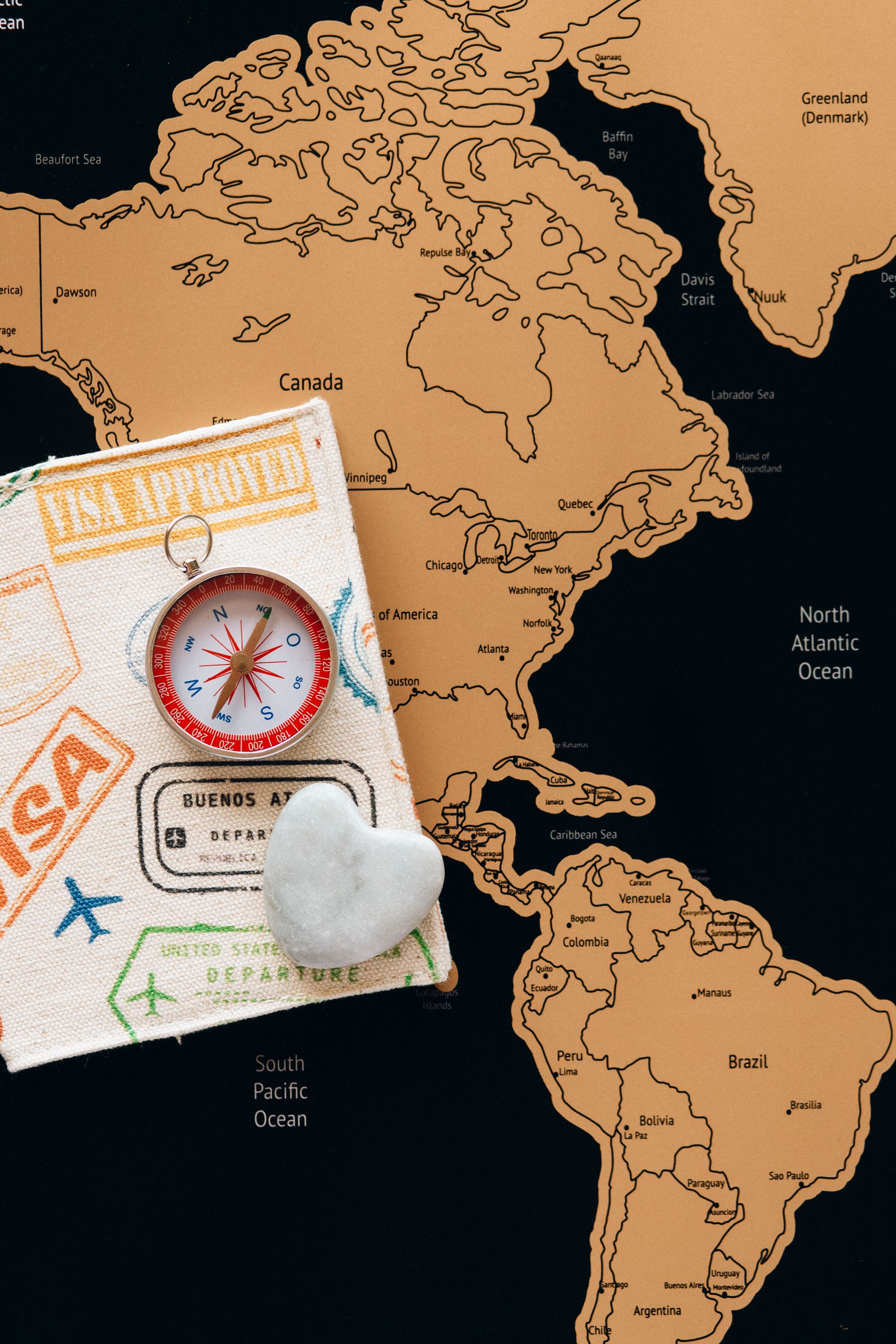 Passport, visa stamps, and a compass laid over a world map